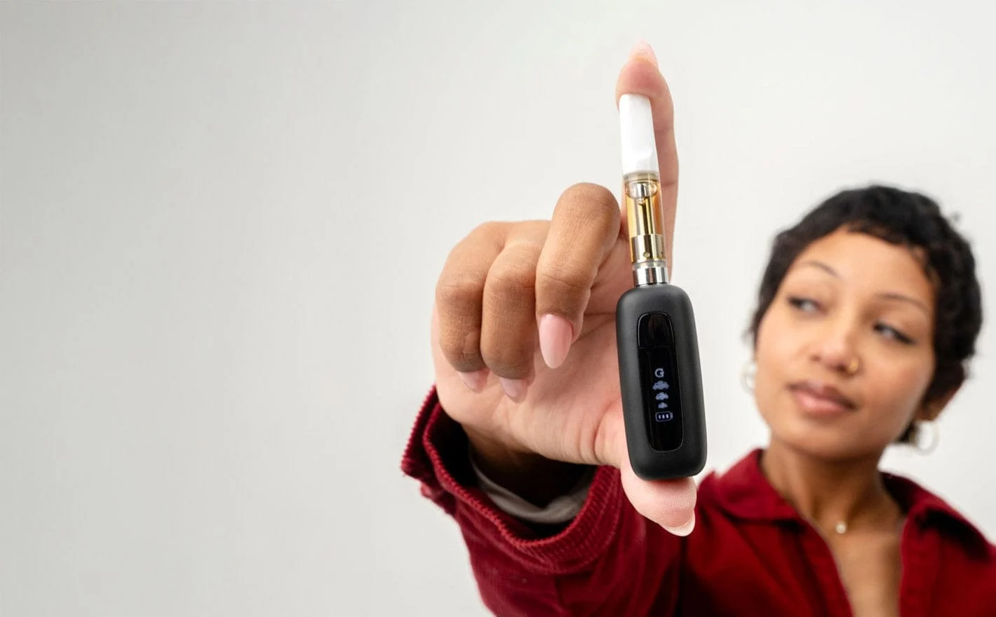 Close-up of a sleek 510 thread vape pen battery with an attached prefilled cannabis oil cartridge on a minimalist white ba...